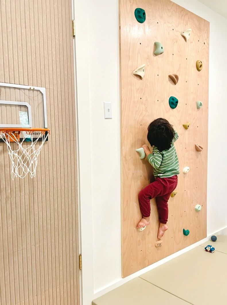 A child on a birch climbing wall beside a basketball hoop